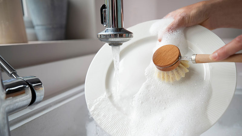 une personne lavant une assiette à la main 